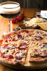 Delicious pizza with salami, tomatoes and dark beer
