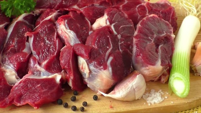 Raw beef on wooden board with garlic and onions
