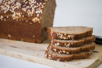 Brotscheiben und Brotlaib auf Holzbrett, Dinkelbrot, nah