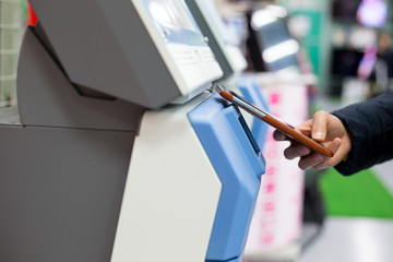 Woman using smart phone for paying on machine by NFC