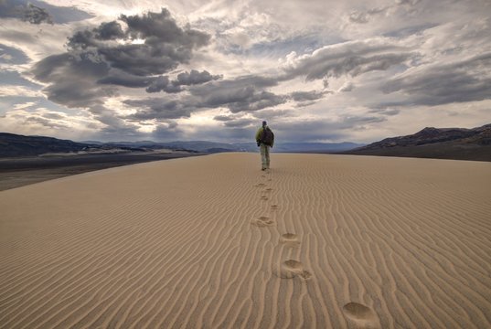 Rear view of a Man walking across the eureka dunes, death valley national park, California, USA
