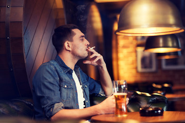 man drinking beer and smoking cigarette at bar