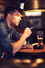 man drinking beer and smoking cigarette at bar