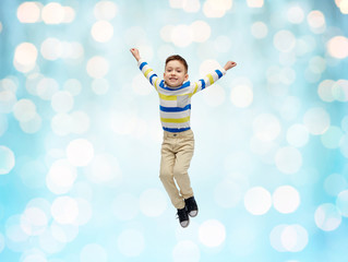 Fototapeta na wymiar happy little boy jumping in air over blue lights