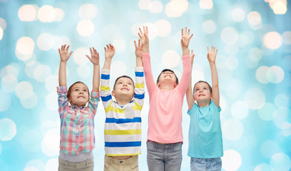 happy children with raised hands over blue lights