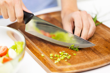 close up of woman chopping green onion with knife