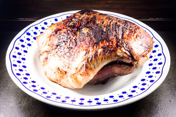roasted pork ham in a dish on dark wooden ambient 