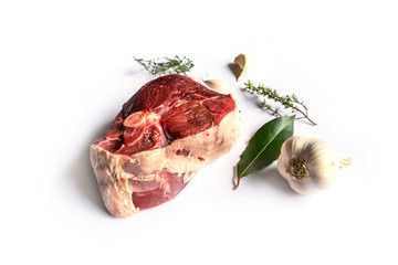 beautiful raw slice of an organic leg of lamb meat with garlic, fresh bay laurel and thyme on a...