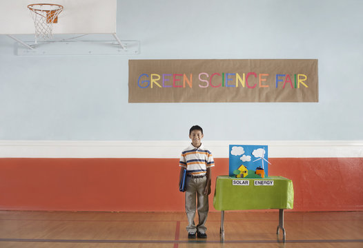 A boy standing under a Green Science Fair sign beside a Solar Power presentation, 