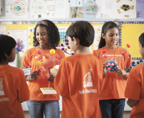 A group of girls and boys wearing the teeshirt of the Science Club, making molecular structure models, 