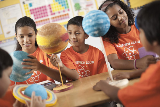 A group of girls and boys wearing the teeshirt of the Science Club, making molecular structure models, 