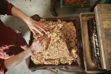 Overhead view of the cider maker pressing the pulp into the frames in the cider press, 