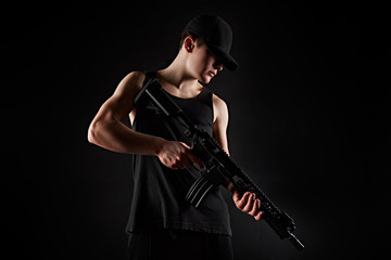 Young wan with gun on black background/Young wan in with rifle in hands on black background poses...