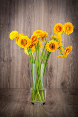 Gerber flowers in the vase on wooden background