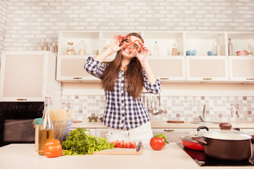 Cheerful comic girl holding slices of pepper near eyes