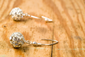 Fashionable earrings with silver and crystal glass isolated on wooden background