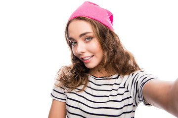 Cute girl with curly hair in pink cap making selfie