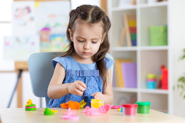 Obraz na płótnie Canvas Kid girl playing with plasticine at home