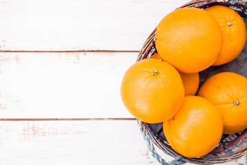 Fresh oranges in basket on wood background