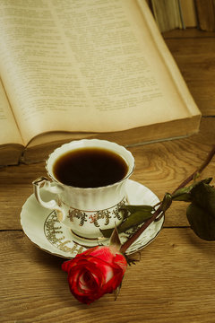 Old books and a cup of coffee with a rose