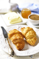 Croissant with butter,honey and cup of coffee.