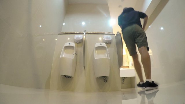 Man Peeing in Toilet with Urinals. 4K 
