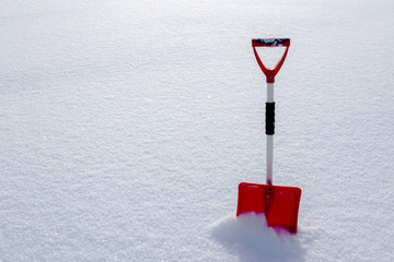 Red snow shovel standing in the snow
