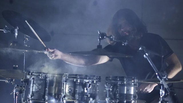 drummer plays the drums in a dark room