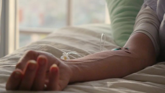 Hand of a patient with pulse meter lying with drop counter on the bed. 1920x1080
