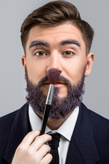 Young man with violet beard posing with make-up brush