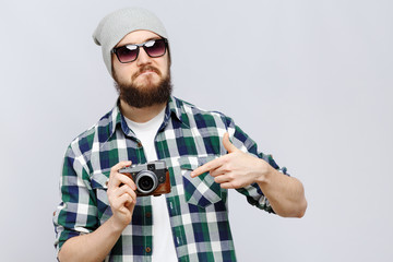 Young hipster holding camera in his hand in studio