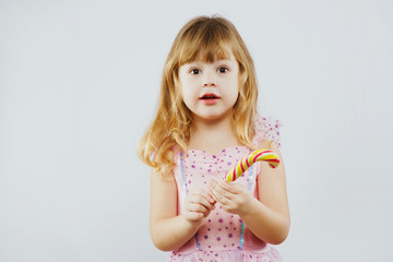 Beautiful little girl holding candy in her hand