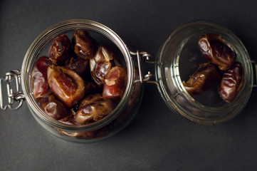 A jar of sweet dates, arabic traditional dessert, black background