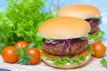 Juicy burgers hamburger with a big beef cutlet, tomato, lettuce and onion on wooden background