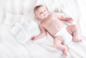 Baby in diaper on a white background with a branch of cotton - obrazy, fototapety, plakaty