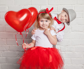 Little kids holding and picking up heart balloons. Valentine's Day and love concept, on white...