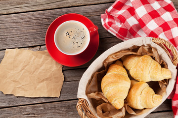 Fresh croissants and coffee on wooden table