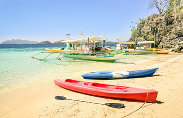 White sand beach with longtail boats and kayaks in Coron Palawan - Beautiful tropical destination in Philippines - Travel concept to nature wonders around the world - Warm sunny afternoon color tones