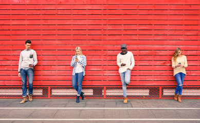 Group of multiracial fashion friends using smartphone with red wood background - Technology...