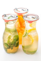 set of three summer lemonade with ice and fruit like lemon, orange, lime and mint leaf, summer drink with soda isolated on white background