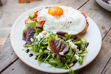 Salad with fried egg  on a wood table