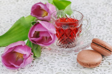 cup of karkadeh red tea with macaroons and tulips