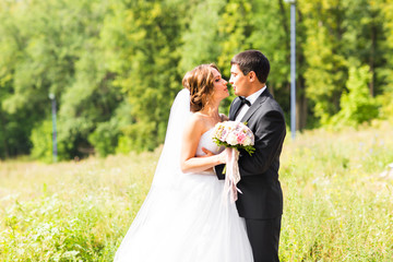 Young wedding couple enjoying romantic moments outside on a summer meadow