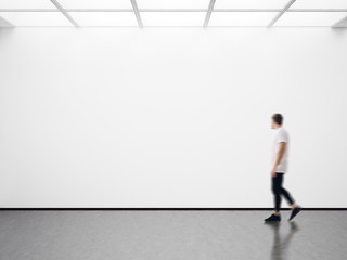 Photo of man in modern gallery looking at the empty canvas. Blank mockup, motion blur  - obrazy, fototapety, plakaty