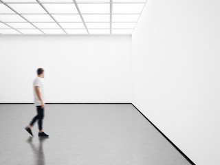 Photo of young man in modern gallery looking at the empty canvas. Blank mockup, motion blur 
