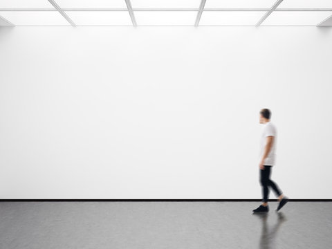 Photo of man in modern gallery looking at the empty canvas. Blank mockup, motion blur 