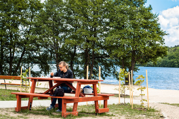 Woman eating in outdoor restaurant by the lake, summer vacation and relaxation time

