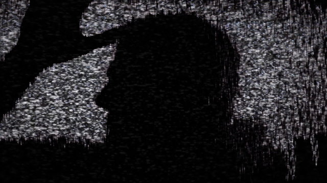 The silhouette of a zombie moving inside an old analogue tv screen. Horror Halloween themed shot.