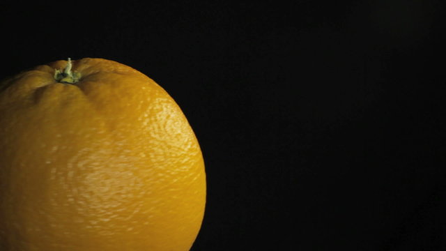 Big juiced orange, macro Spins on dark background  
