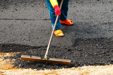 Close-up tracked paver at asphalt pavement works for road under construction.